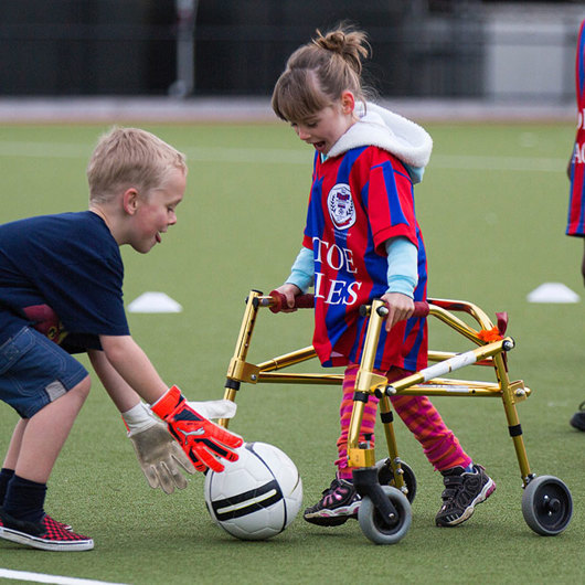Girl with walking frame shooting for goal in soccer