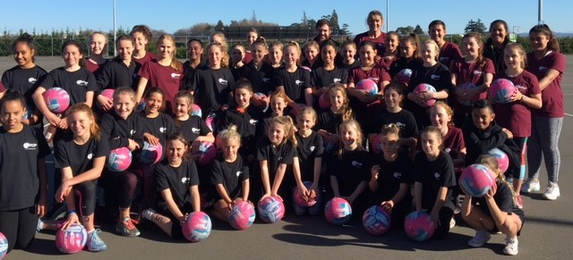 Junior netball teams holding netballs