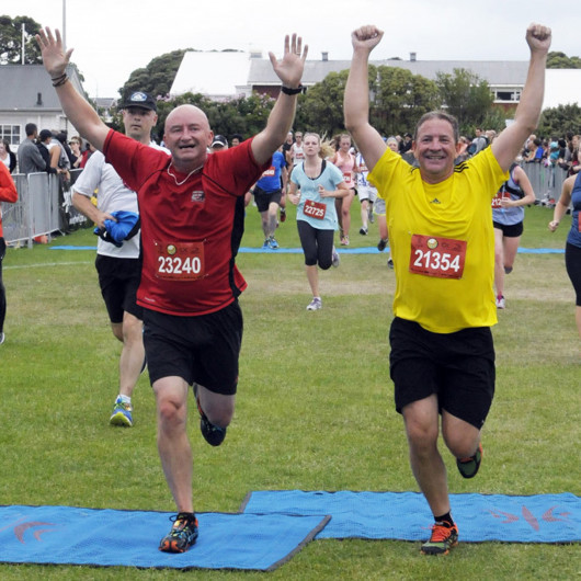 Two adults crossing a finish line in a running race