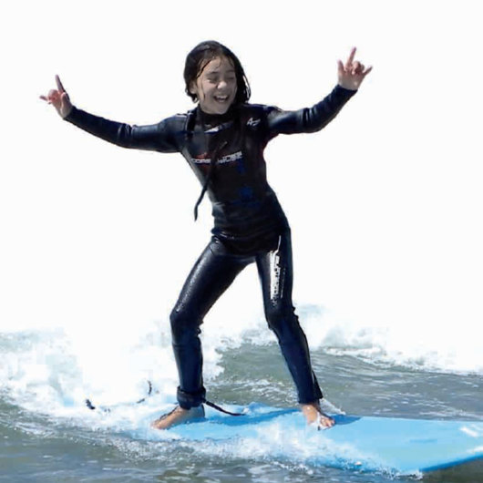 Tamariki catching a wave on surfboard
