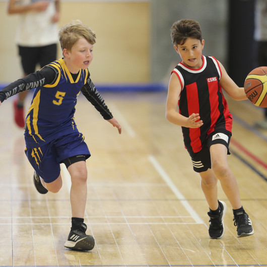Two tamariki playing basketball