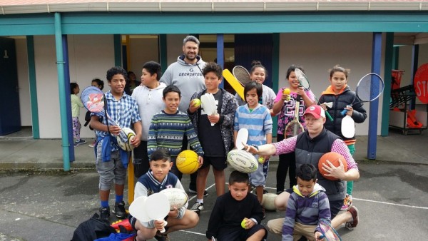 Group of kids and their teachers holding sporting equipment