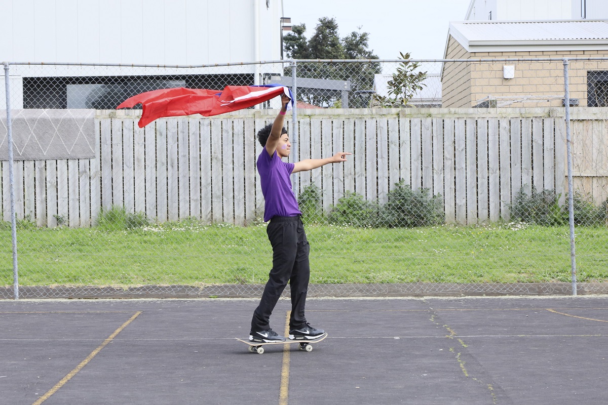 Young person on a skateboard waving a flag