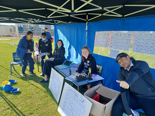 Group of students keeping score under a canopy