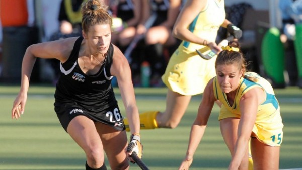 Two players in a hockey game reaching for a ball