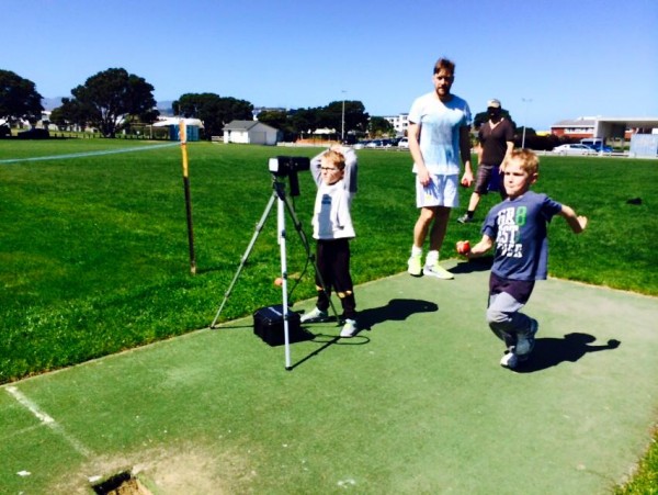 Family filming son bowling a cricket ball