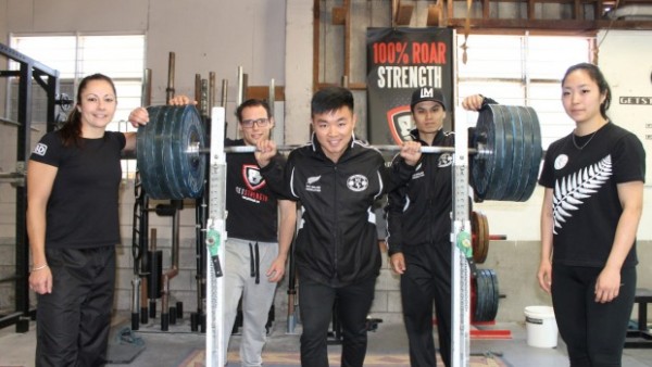 5 people at the gym, one of them is backsquatting