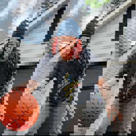 Young woman bouncing basketball in driveway
