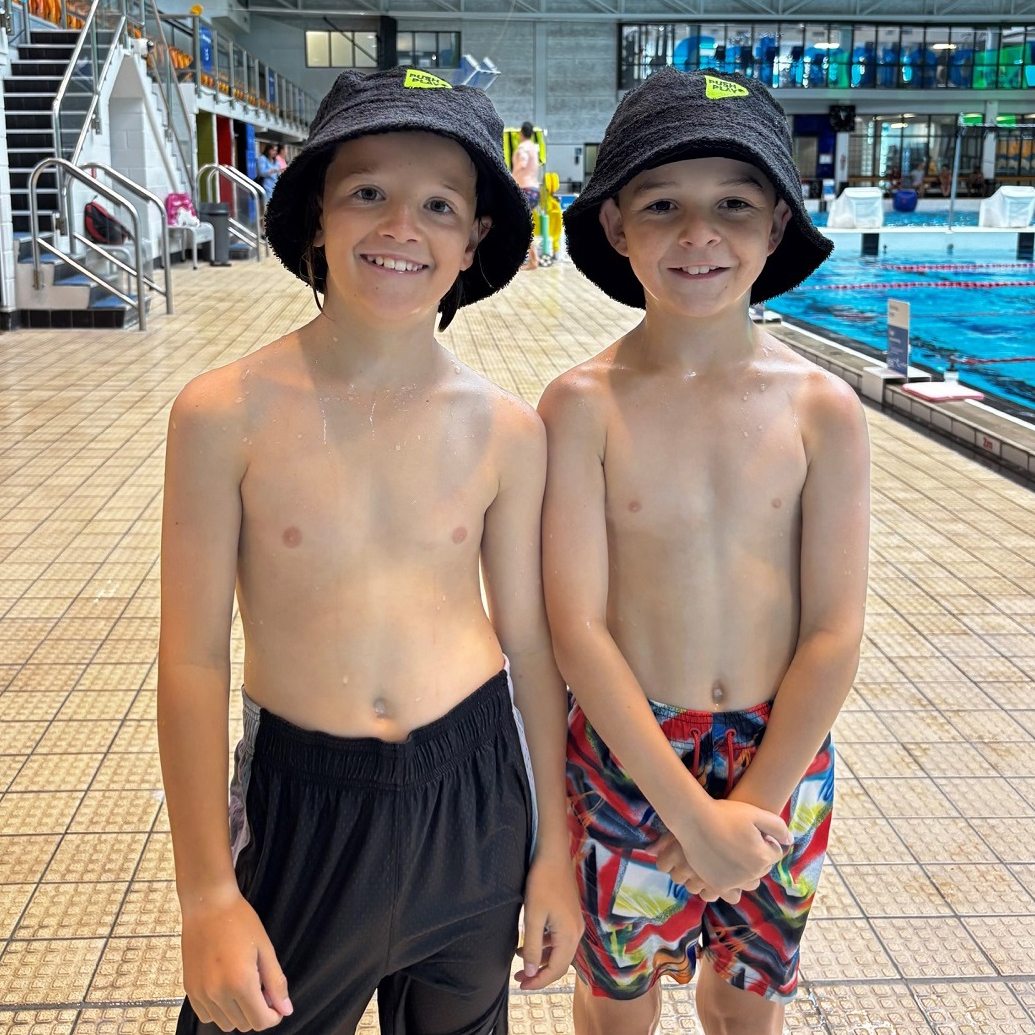 Two tamariki standing by a pool