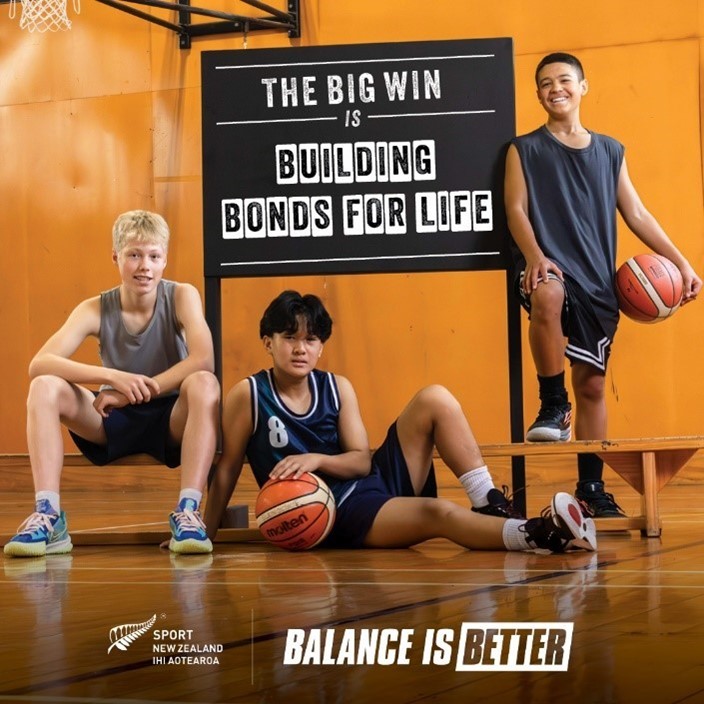 Three young men looking to the camera on a basketball court