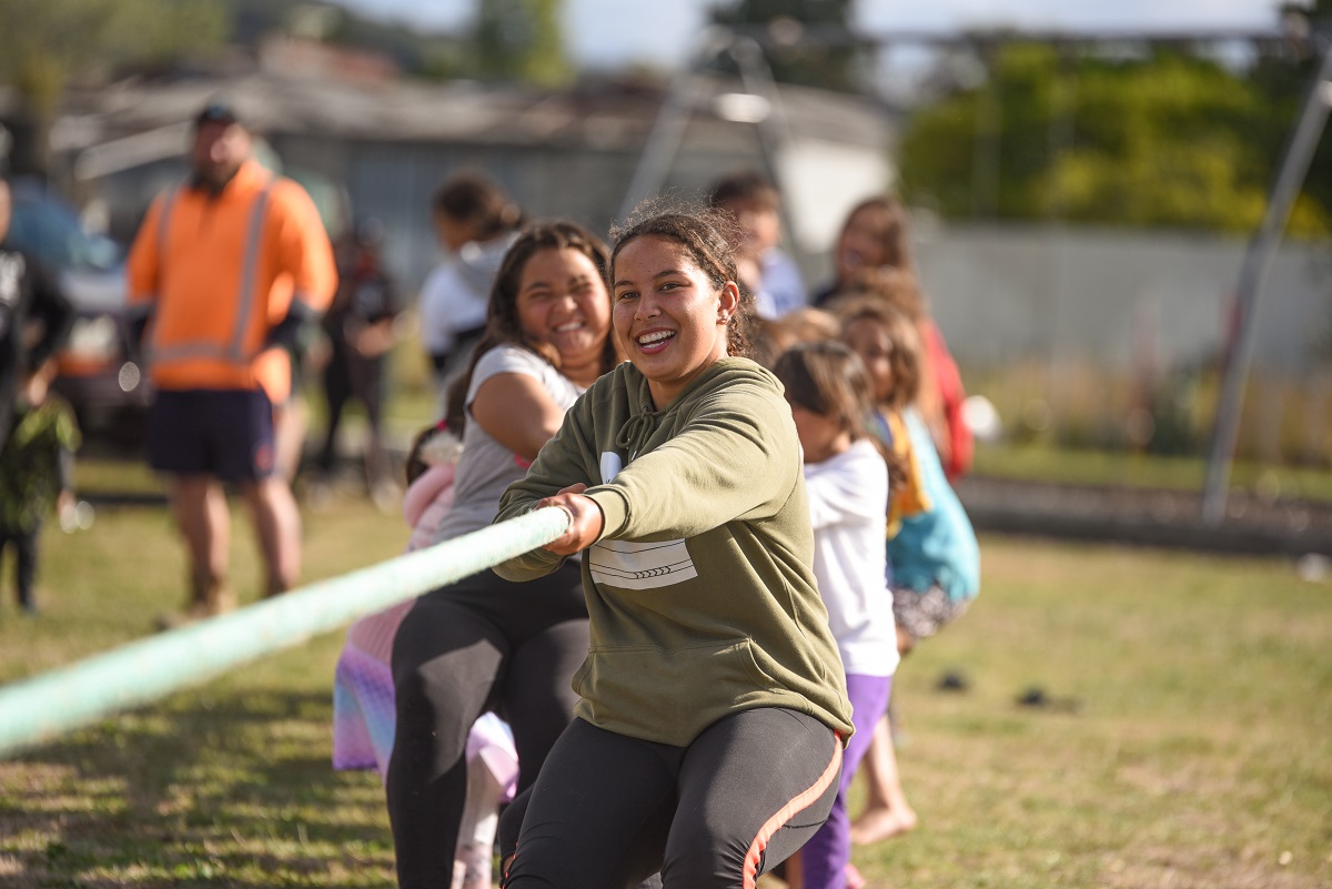 Yound people playing tug of war looking to camera