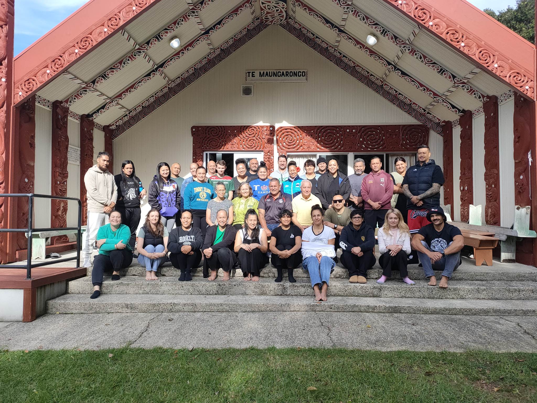 Group of people standing in front of a marae