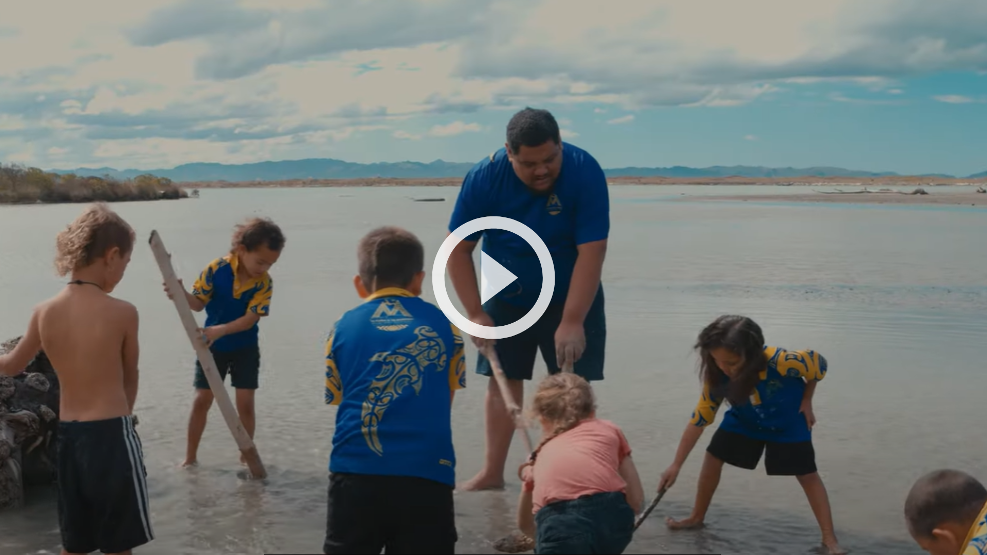 Tamariki playing on a beach with sticks