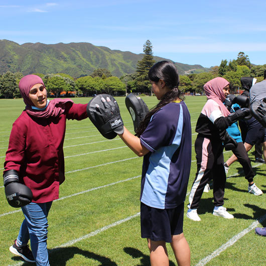 Rangatahi wahine boxing training on an athletics field