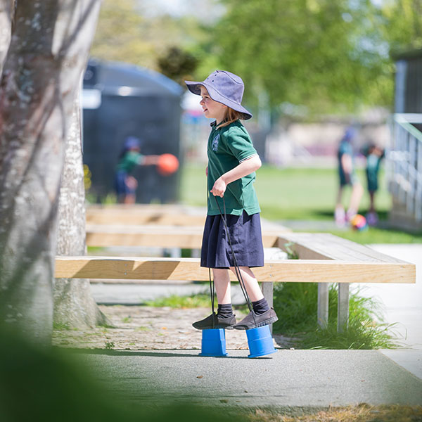 child standing on bucket stilts