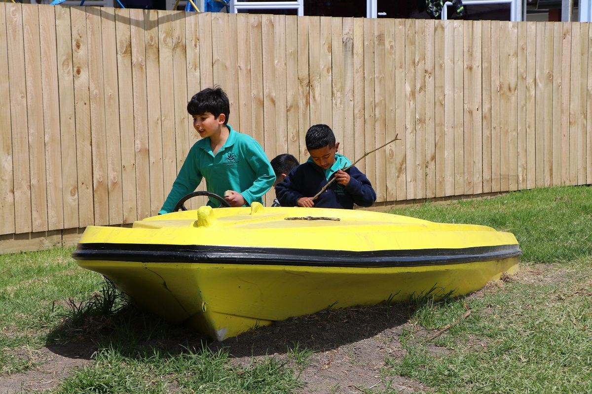 Three boys in a boat sitting on grass