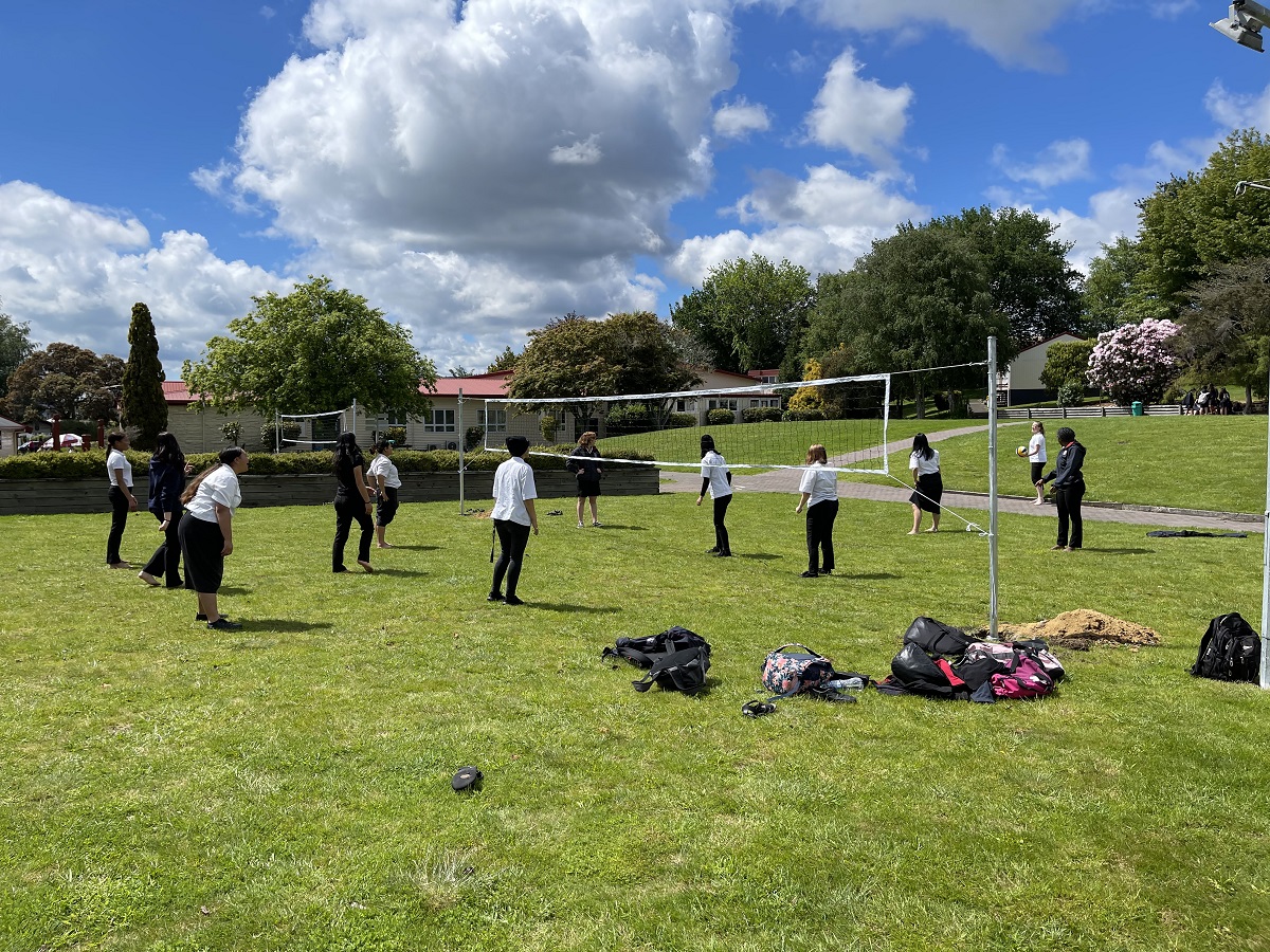 Young people playing volleyball on a field
