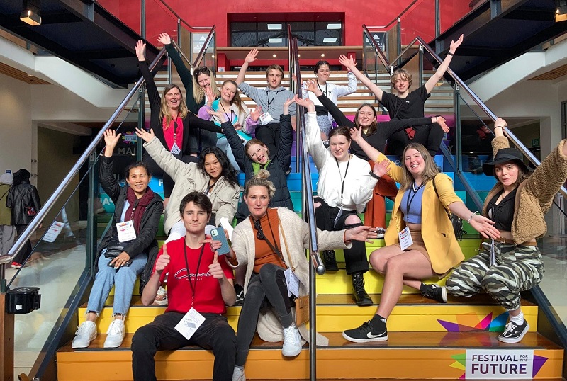 Group of people sitting on a staircase with raised arms