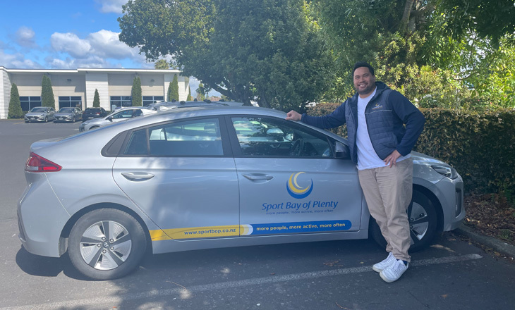 Man standing by hybrid car