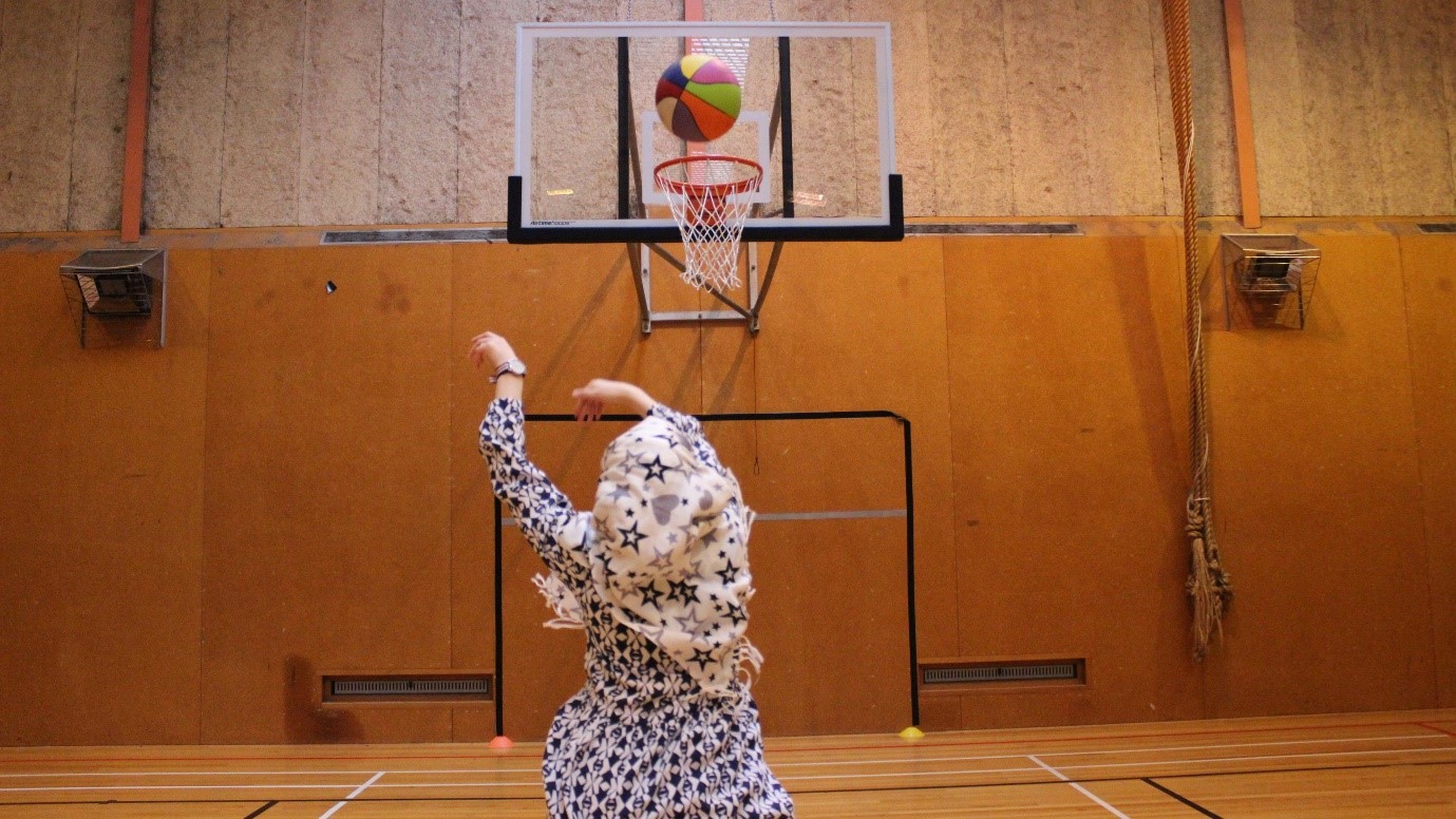 Girl throwing ball into a hoop in a gymnasium