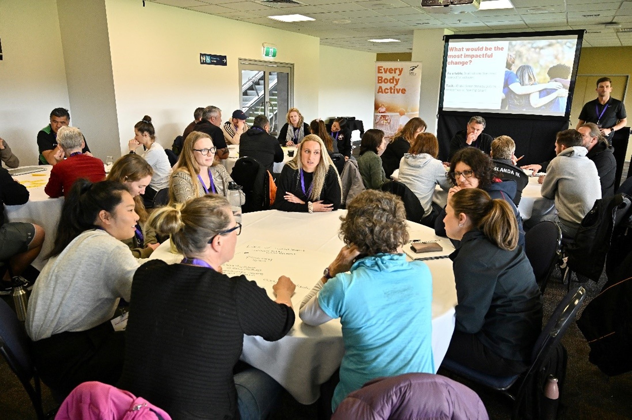 Group of peple sitting around a round table discussing Healthy Active Learning