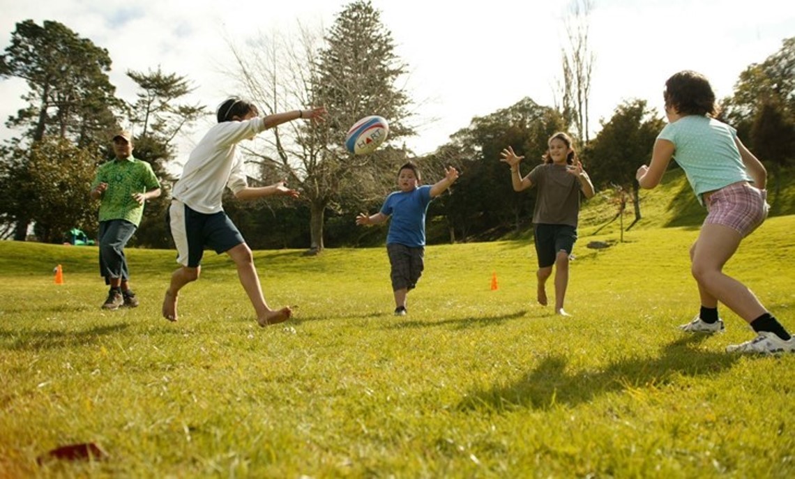 Kids playing rugby outside on a field