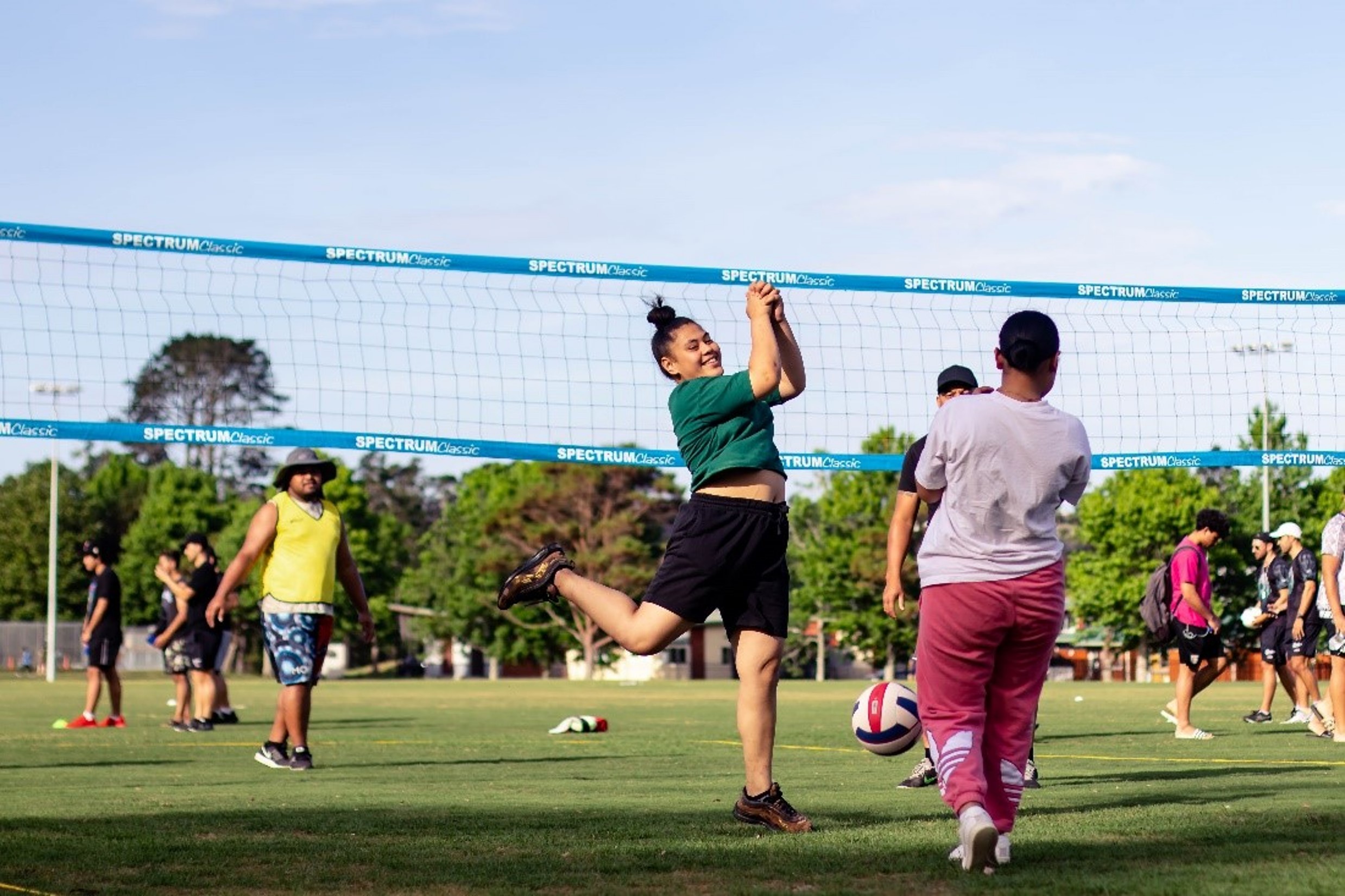 Young women play volleyball on a field