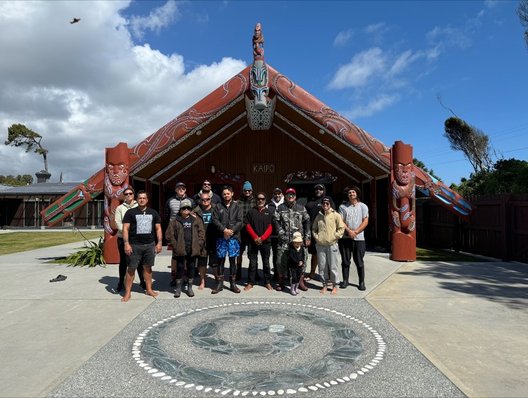 Group of people standing in front of a marae