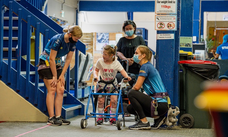 Climbing trainers assisting a child at a climbing gym